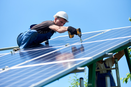 Installing innovative solar panel on metallic carcass using electric drill. Modern solution for natural resources saving, using renewable solar energy. Environment friendly, green energy. Ecological.の写真素材