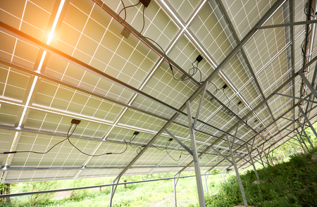 Interior of stand-alone photo voltaic solar system secured on metal rear legs on green grass, lit by summer sun. Alternative energy, environment protection and cheap electricity production concept.の写真素材