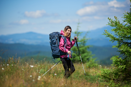 Young active female climber with backpack and trekking sticksの写真素材