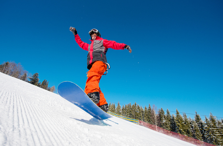 Snowboarder in the air while riding on the slope in the mountains on a beautiful sunny winter day. Blue sky on the background active lifestyle sports conceptの写真素材