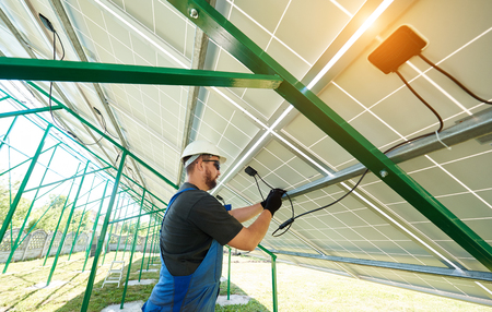 Male worker installing solar panels during sunny day. Perfect solution for saving energy of sun, environmental resources. New ecological technologies for ecology. Economical, innovative.の写真素材
