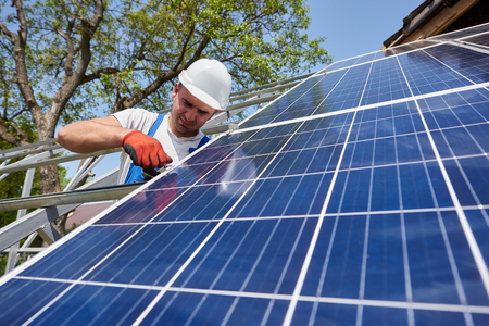 Professional technician attaching solar photo voltaic panel to high metal platform. Exterior solar system installation, cheap green ecological energy production concept.の写真素材
