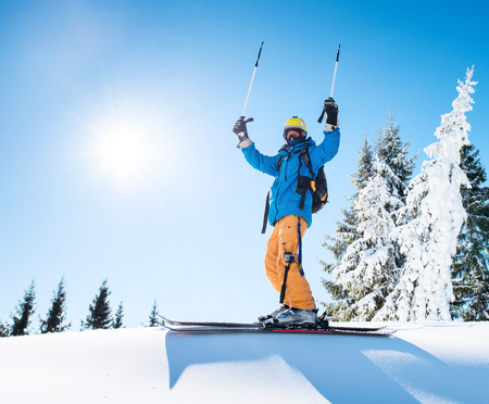Professional freeride skier holding ski poles raising his arms in the air on the top of the mountain achievement leadership celebration winning happiness positivity gesturing riding lifestyle extreme.の写真素材