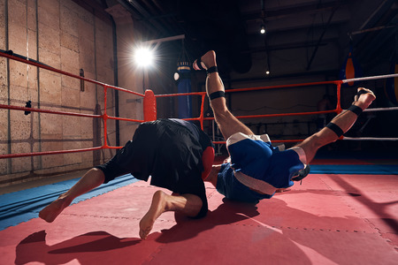 professional fighter practicing mma with his trainer in the ring at the health clubの写真素材