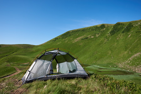 View of one tent among mountains. Little camping near lake in Carpathian mountains in the morning time. Summer season and concept of recreation and relax, alone with nature.の写真素材
