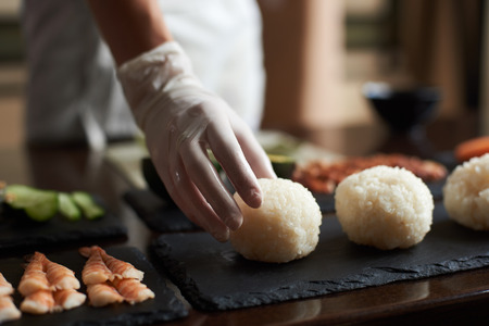 Close-up view of process of cooking rolling sushi at restaurant . Chef is preparing ingredients for rollsの写真素材