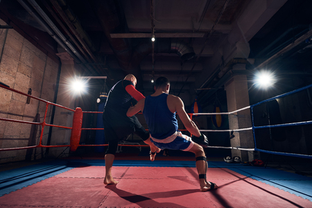 fit male boxer training mma with his trainer in the ring at the health clubの写真素材