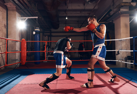 Two young male fighters training kickboxing in the ring at the health clubの写真素材