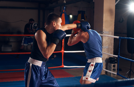 Anger man boxer exercising kickboxing with sparring partner in the ring at the sport clubの写真素材