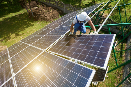 Risky work: mounting solar batteries on green metallic carcass. Environment friendly, green energy. Modern solution for natural resources saving, using renewable solar energy. New high-tech exterior.の写真素材