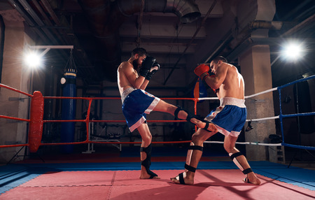 Healthy male boxer training kickboxing with sparring partner in the ring at the sport clubの写真素材