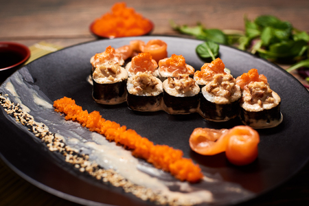 Close up of tasty fresh sushi rolls with fish and rice on black plate. Sushi rolls served on a wooden table in a restaurantの写真素材