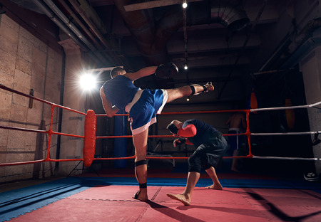 young man fighter training mma with his trainer, fighting in the ring at the health clubの写真素材