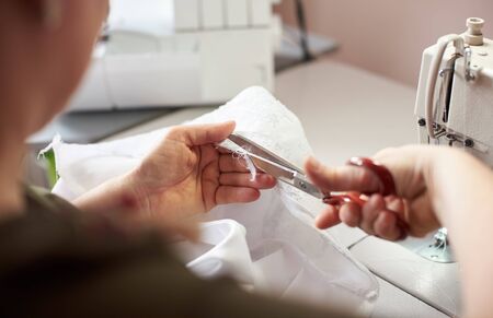 Close up view of woman, laboring at working place. Female hand using scissors for cutting off...