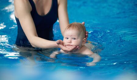 Little infant swimmer. Cropped view of mother standing in water and training her newborn baby...