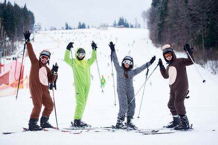 Bukovel, Ukraine - December 09, 2018: skiers men and woman on skis in ski mask dressed in animals costumes, smiling and raising their hands up with ski poles, standing at foot of snowy slopeのeditorial素材