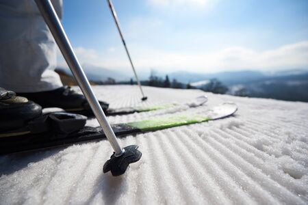 Close-up part of skier legs in ski shoes in white snow, beautiful misty winter mountain landscape and blue sky copy space background. Sports and recreation, active lifestyle concept.の写真素材