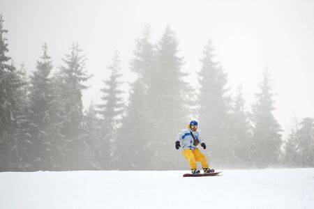 Bukovel, Ukraine - December 09, 2018: male snowboarder in ski mask and in bright ski suit freeriding...