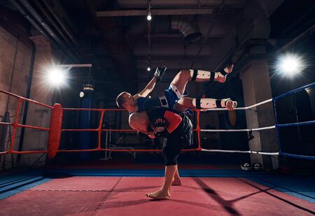 athlete man fighter training mma with his trainer, fighting in the ring at the health clubの写真素材