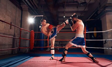 Two athletic sportsmen kickboxers practicing kickboxing in the ring at the sport clubの写真素材