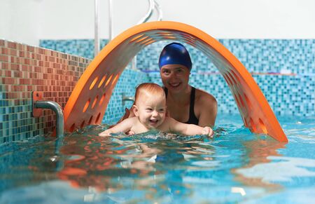 Playful active training in swimming pool. Little cute boy is learning how to float with his supportive mother. Concept of healthy familyの写真素材