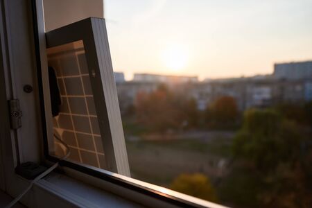 View from inside at solar battery standing on the window of a high-rise residential building....