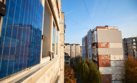 Solar panel on balcony of multi-storey building against background of residential area of city with clear blue sky in the warm evening.の写真素材