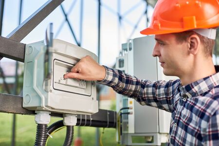 Close up of hand man engineer pushing button at the electrical equipment on solar power station with...