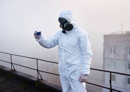 Man working on roof of high building, researching on samples, gathered in contaminated area,...