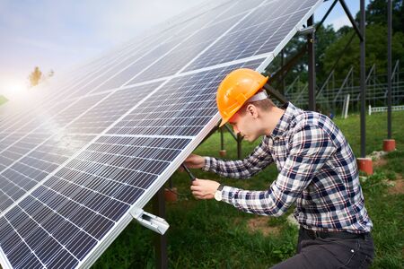Engineer connecting solar panels on a green plantation. Home construction. Solar station development concept. Construction industry.の写真素材