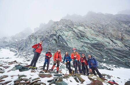 Male alpinists standing on rocks and stones while taking break from hiking in winter mountains....