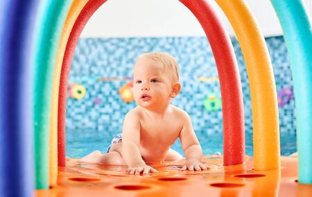 Portrait of cute little boy is lying on a floating colorful construction in the swimming pool. Concept of healthy childhoodの写真素材