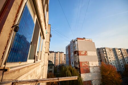 Solar panel on the balcony of multi-storey building against background of residential area of the city with clear blue sky on a warm day.の写真素材