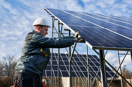 Horizontal snapshot of process of installing solar panels on metal ground mounting by a technician...