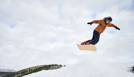 Concept of extreme kinds of sport. Snowboarder wearing colorful clothing flying up high with...