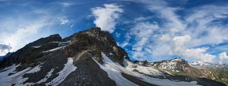 Panoramic scenery in sunny day with blue sky and clouds, beautiful mountains area with snow. Gorgeous mountain ridge with high rocky peaks, wonderland in Alps.の写真素材