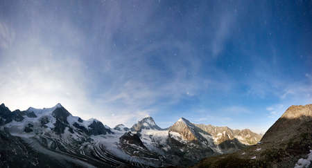 Amazing scenery in evening, beautiful mountains area with white snow. Gorgeous mountain ridge with high rocky peaks Ober Gabelhorn and Dent Blanche with shining stars in sky, wonderland.の写真素材