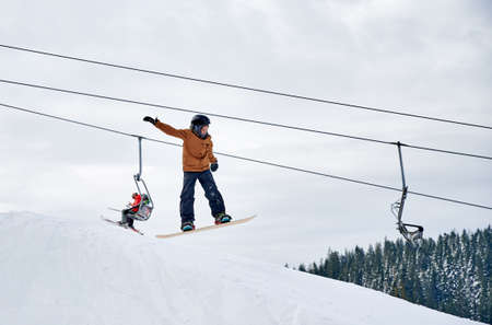 Snowboarder doing tricks in the mountains in winter season, flying up high with snowboard against...