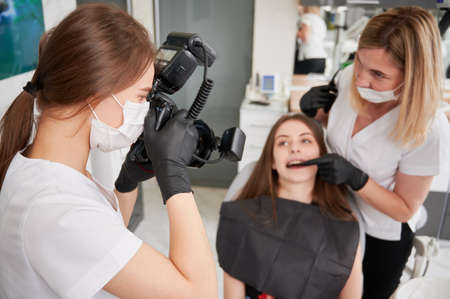 Dentist taking picture of female patient in dental office.の写真素材
