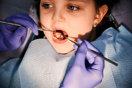 Female dentist examining little girl teeth in dental office.の写真素材
