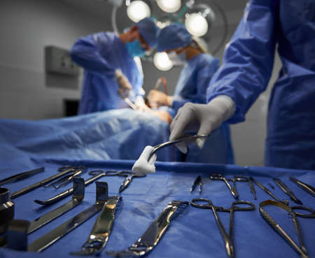 Doctors using medical instruments during plastic surgery.