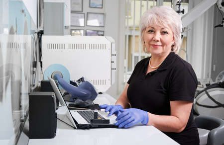 Portrait of female doctor sitting at computer in dental clinic