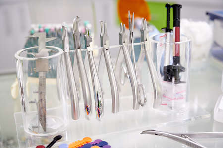 Close-up snapshot of dental tools hanging on transparent stand. Orthodontic tongs and forceps on the table. Steel instruments for dental use. Concept of dentistry, medical instrumentsの写真素材