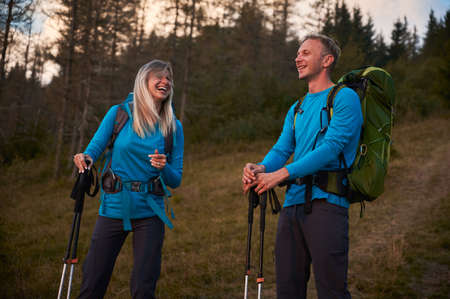 Couple of hikers having fun together while walking outdoors on forest background. Pair of tourists...