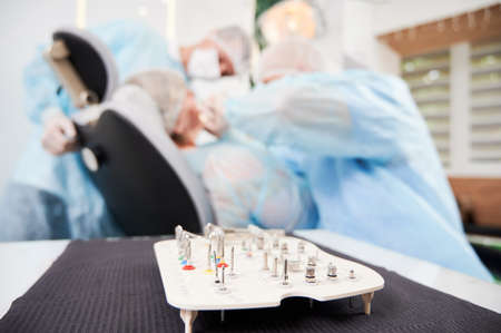 Close-up snapshot of set of metal heads for dental bur machine opened on table on foreground,...