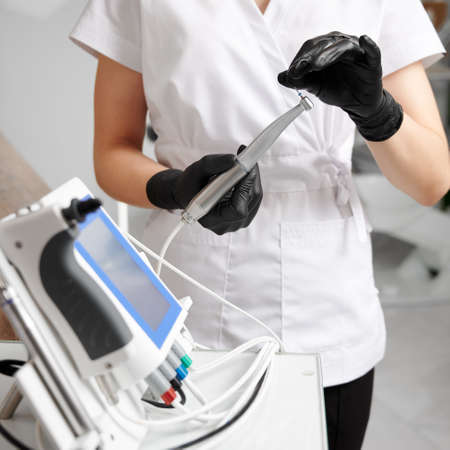 Dentist wearing white uniform and black gloves, working with all-in-one device concept for...