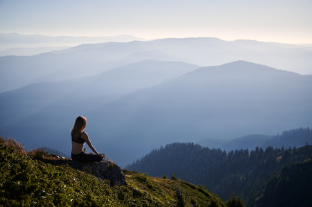 Young woman doing meditation on nature with incredible view in the morning. Concept of healthy lifestyle.の写真素材