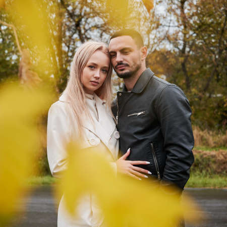 Portrait of young couple in love. Man and woman posing near the road, looking to the camera. View...
