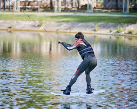 Wakeboarder surfing on lake. Young man surfer having fun wakeboarding in the cable park. Water sport, outdoor activity concept.の写真素材