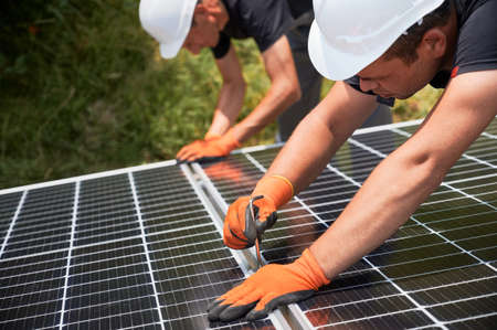 Workers installing solar panel at sunny daytime. Renewable and ecological energy. Idea of...